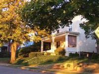Phot of house on residentia street - house is on a hill adn has porch across front of the house